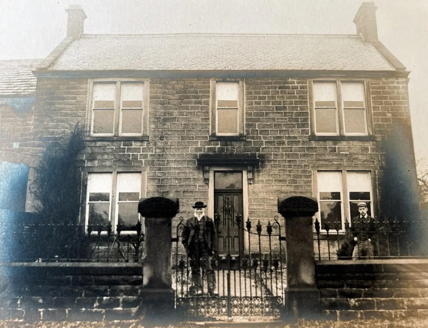 A black and white photo of a man standing in front of a house.